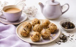 紅茶のカップとティーポット、丸い一口サイズのグラノーラを配した上品な食品静物イメージ
