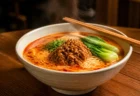 湯気の立つ担々麺、木製テーブルの上の丼と箸
