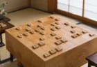 和室に置かれた木製の将棋盤と駒台、対局途中の盤面