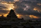 夕暮れの雷雲の下に浮かぶ黒い天守の城のシルエット
