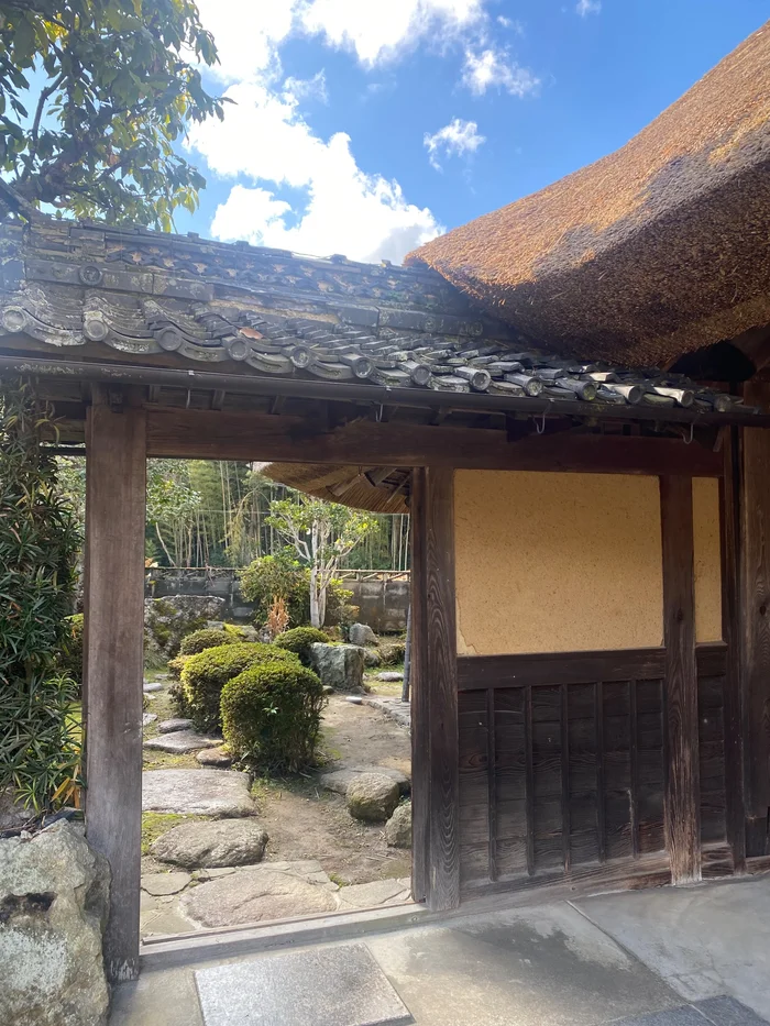 画像 はなとねの敷地内にある瓦屋根の門と、その奥の飛び石の庭