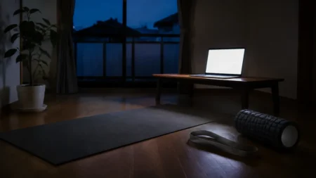 夜明け前の部屋に広げられたヨガマットとノートパソコン