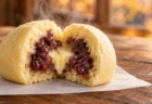 湯気の立つホットケーキ風の蒸しまんを割った断面から、つぶあんとバター色のフィリングがのぞく様子