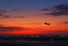 夕暮れの空港滑走路から離陸していく旅客機のシルエット