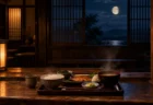 月明かりが差し込む夜の木造食堂のカウンターに置かれた湯気の立つ一人前の膳