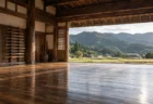 のどかな田舎の村の道場。木の床に木剣が立てかけられ、開いた戸の外に畑と山並みが見える