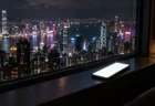 夜の大都市を見下ろす窓辺に置かれた、画面が光るスマートフォン