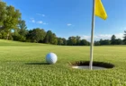 晴天のゴルフ場のグリーンとカップに向かって転がるボール