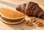 木のテーブルに置かれたチョコレートクリームの洋菓子とチョコクロワッサン、くるみ