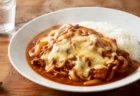 木のテーブルに置かれた白い深皿のトマト系ハヤシライス、とろけるチーズと湯気のイメージ