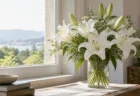 柔らかな自然光が差し込む窓辺に置かれた白いユリの花束