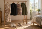 朝日が差し込む部屋のハンガーラックに並ぶ系統の違う服と、床に置かれたスニーカーとパンプス