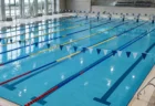 背泳ぎ用のフラッグが張られた屋内競泳プールの水面とレーンロープ