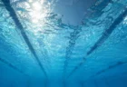 水中から見上げた競泳プールの水面に揺れる照明の光
