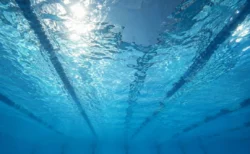 水中から見上げた競泳プールの水面に揺れる照明の光