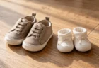 木目の床に並ぶ、少し大きめの子ども用の靴と新品の小さなベビーシューズ