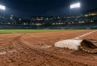 ナイター照明に照らされたプロ野球場の一塁ベース付近と、土に残るスライディングの跡