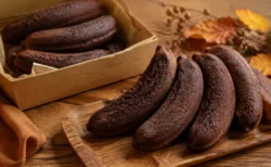 木箱と皿に並んだチョコレート色のバナナ形焼き菓子、秋の紅葉と共に