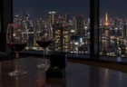 夜景を望むマンションの一室のテーブルに置かれた婚約指輪の小箱と2つのワイングラス