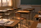 夕方の光が差し込む教室。木製の机と椅子が並び、1席だけ椅子が引き出されて机の上が空いている