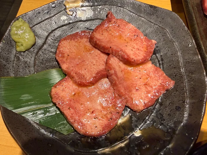 竹の葉とわさびが添えられた焼く前の上タン塩
