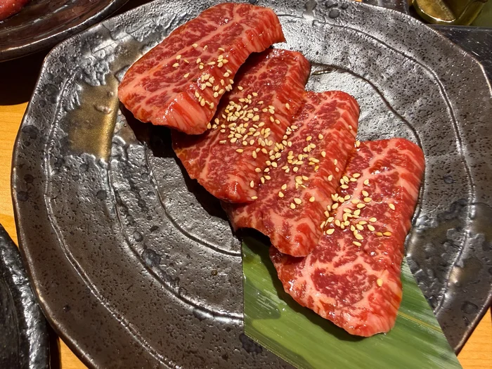 竹の葉を敷いたお皿に盛られた、サシの入った焼く前のロース