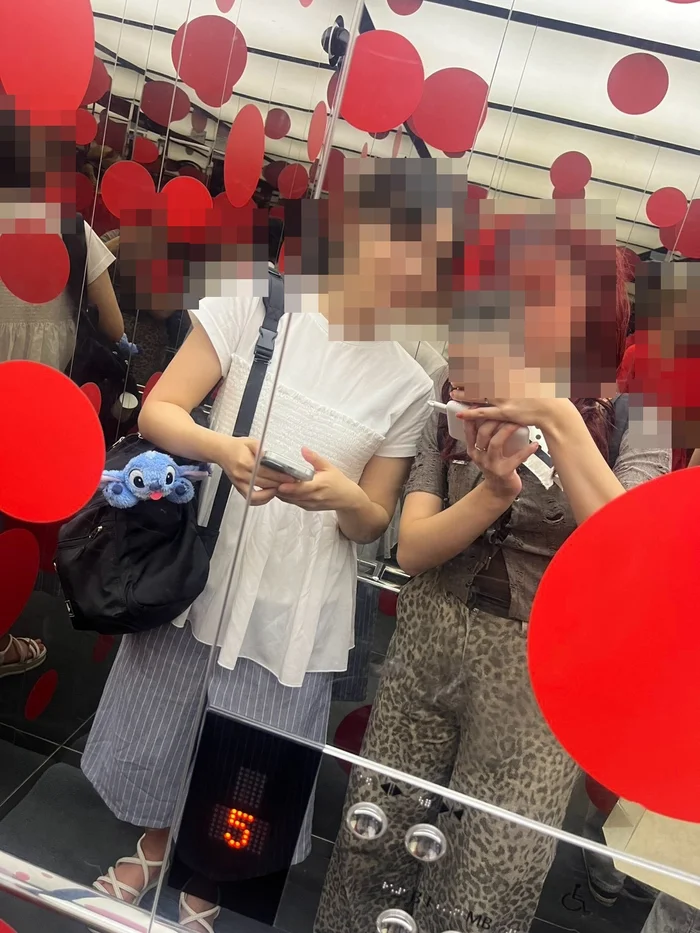 四方が鏡張りで赤い水玉が浮かぶエレベーターの内部