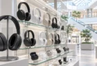 明るい家電売場のガラス棚に並ぶヘッドホンと、奥に広がる吹き抜けの店内