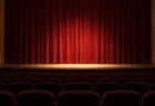 劇場の客席から見た幕の下りた舞台と柔らかなスポットライト