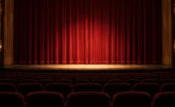 劇場の客席から見た幕の下りた舞台と柔らかなスポットライト