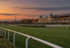 夕暮れのヨーロッパの競馬場の芝コースと、遠くに見える街並みと鉄塔