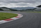 曇り空の下、赤白の縁石が続くロードレースサーキットのコーナーとスタンド