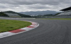 曇り空の下、赤白の縁石が続くロードレースサーキットのコーナーとスタンド