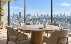 高層階のラウンジに置かれた大きな円卓と椅子、窓の外に昼の東京の街並み