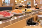 回転寿司のレーンを流れる寿司皿と、テーブル席の皿投入口