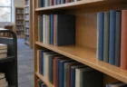 学校図書館の書架の一角だけ本が抜かれて空いた棚と、脇に置かれたブックカート