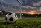 夕暮れのスタジアムでゴールネットの手前に置かれたサッカーボール