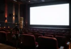 無人の映画館で白く光るスクリーンと、手前に置かれた収録用のスタンドマイクとヘッドホン