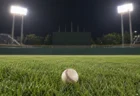ナイター照明に照らされた野球場の外野の芝生に置かれた硬式野球ボール