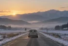 冬の朝、雪の残る田舎道を走る小さな車の後ろ姿