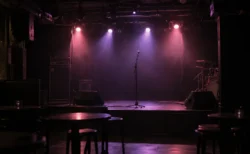 照明を落とした無人のライブハウスのステージとマイクスタンド