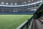 試合のない昼のドーム球場、誰もいないベンチと人工芝の外野