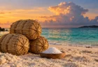 夕方の沖縄の砂浜に置かれた稲わらの俵と塩を盛った木の小皿、奥にエメラルドグリーンの海