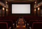 上映が終わった小さな映画館の客席と、明かりの落ちたスクリーン