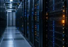 薄暗いデータセンターに並ぶサーバーラックと、青とオレンジに光る状態ランプ