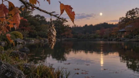 夕暮れの池のほとりで、秋の木の枝からミノムシがぶら下がり、水面に月が映る風景のイメージ