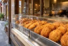 商店街の精肉店のショーケースに並ぶ揚げたてのコロッケ
