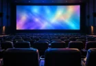暗い映画館の無人の客席と、カラフルな光が映る大きなスクリーン