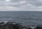 曇り空の下に広がる灰色の海と、水平線にうっすら見える対岸の陸影
