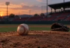 夕暮れの野球場のピッチャーマウンドに置かれた使い込まれた硬式ボールと投手用グラブ